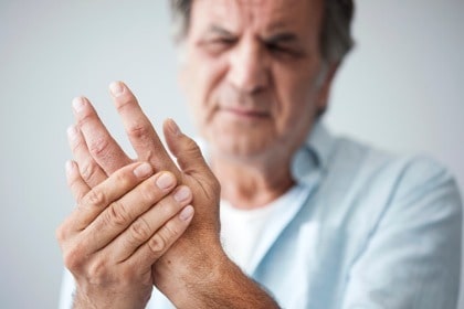 middle age man with finger pain rubbing sore joints due to arthritis