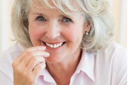 smiling senior woman taking supplement pill