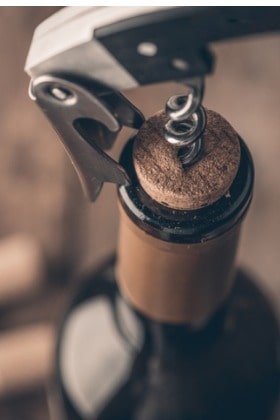 corkscrew removing cork from bottle of red wine