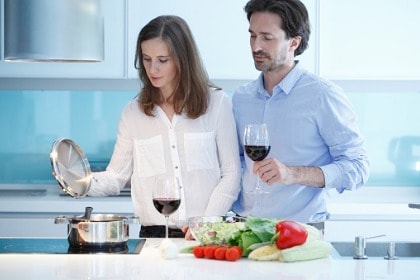 couple cooking healthy dinner in kitchen drinking red wine for health