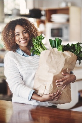 woman-holding-grocery-bag-healthy-foods-leafy-greens