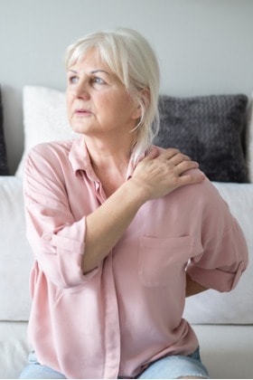 woman-with-back-shoulder-pain-sitting-on-couch