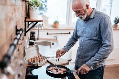 smiling-senior-man-cooking-bacon-eggs-for-keto-breakfast