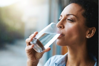 woman-drinking-glass-of-water-looking-outside