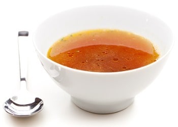 clear-bone-broth-with-spoon-next-to-bowl