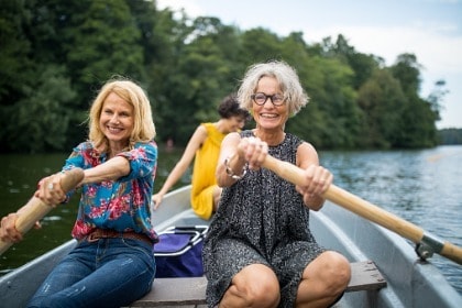 smiling-female-friends-rowing-boat-in-lake-having-fun-in-nature