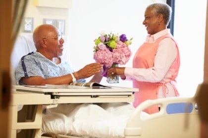 volunteer-giving-flowers-to-male-patient-hospital-room