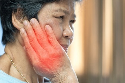 mature-woman-with-tmj-temporomandibular-joint-and-muscle-disorder-clutches-jaw-in-pain