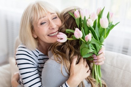 woman-holding-flowers-hugging-daughter