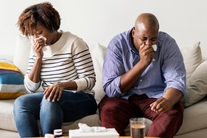 couple-sick-at-home-on-the-sofa-coughing-sneezing