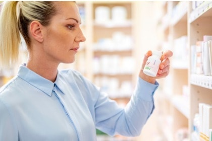 woman-shopping-at-pharmacy-looking-at-vitamin-bottle