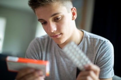 young-teenage-boy-holding-prescription-medication