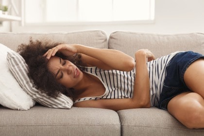 young woman with headache lying on couch