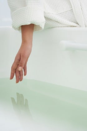 womans-hand-touching-water-in-bath-tub