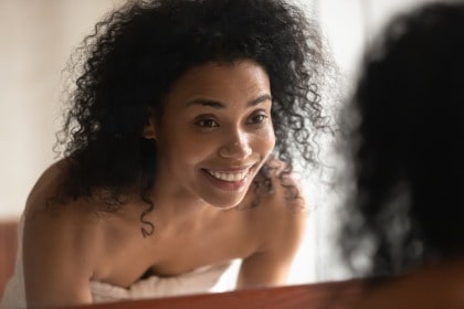 skincare-routine-woman-looking-in-bathroom-mirror