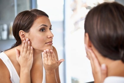 woman-examing-face-skin-in-mirror