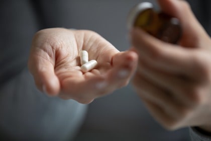 hand-of-young-woman-holding-pills