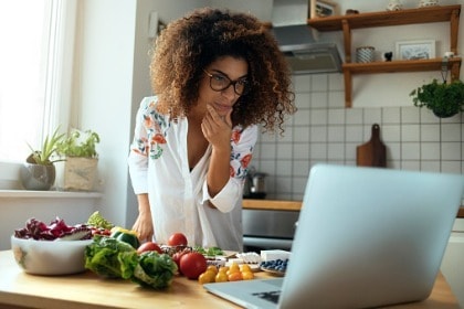woman-at-kitchen-counter-with-healthy-food-looking-for-recipes-on-laptop