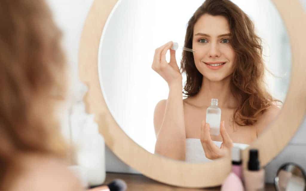 Photo of woman applying raspberry seed oil to her clean skin