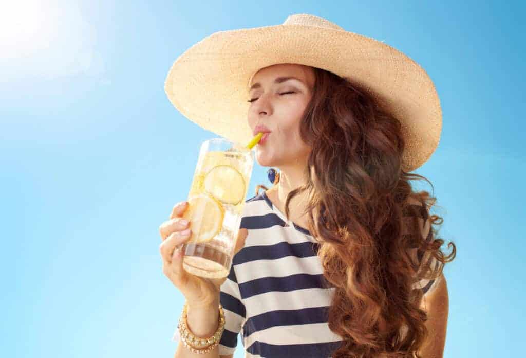 Woman hydrating in the summer with lemon water.
