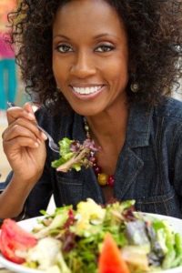 happy African American woman eating salad