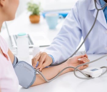 doctor checking woman's blood pressure