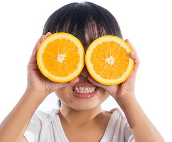 child using oranges as glasses