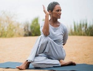 African American woman over 50 doing yoga stretch on mat