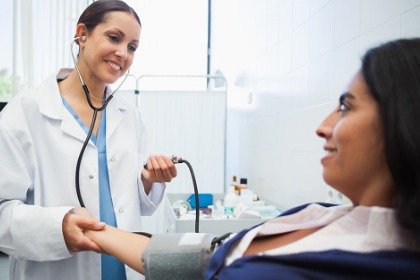 doctor checking female patient's blood pressure