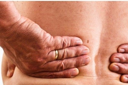 mature man with lower back pain holding back