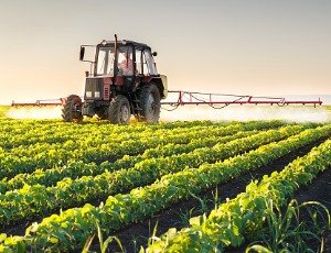 tractor spraying pesticides on soybean crop