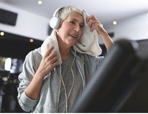 woman on exercise machine at gym wiping away perspiration with towel