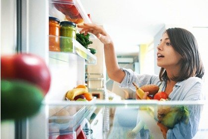 woman picking fruits and vegetables from fridge